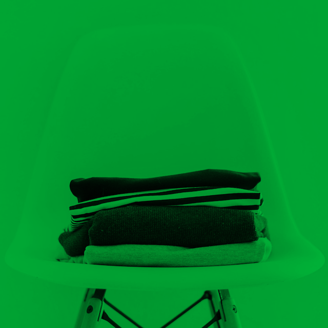 A chair with a stack of clothes on it, all in a green-black tint