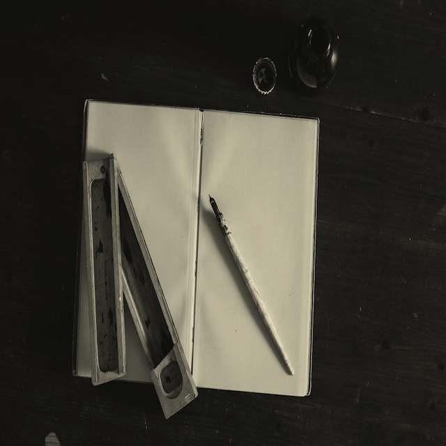 A blank, open journal with an ink pen and other items on top