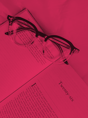 An opened book with reading glasses on top