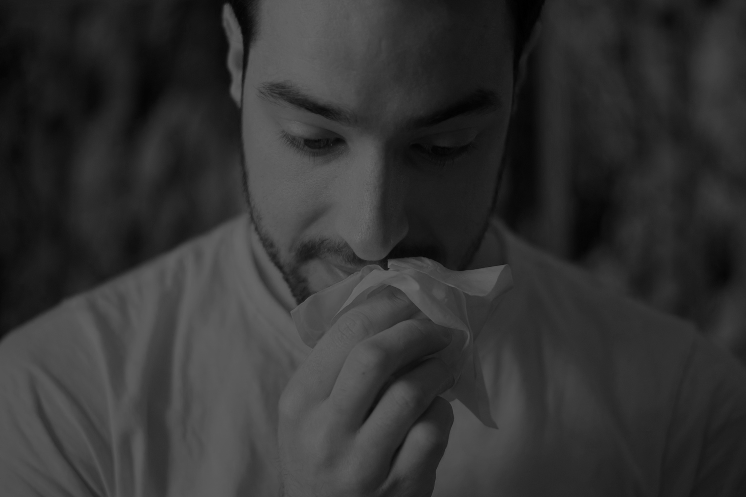 a man who is covering his sneeze by having a tissue